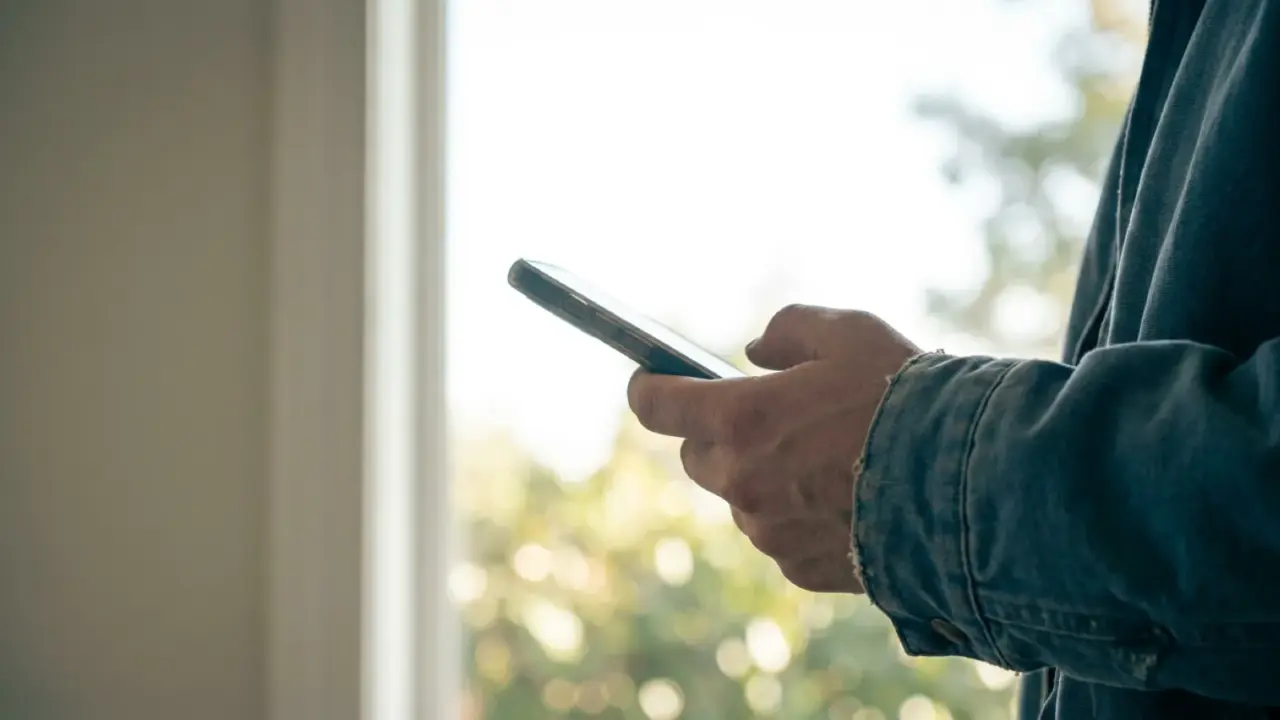A phone held up in one hand against a bright outdoor background