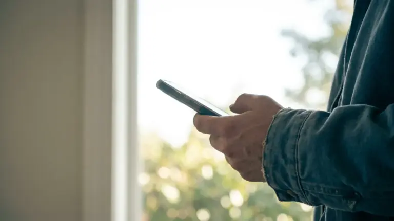 A phone held up in one hand against a bright outdoor background